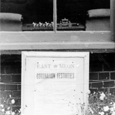 Window during Coronation with poster and miniature state coach and horses.