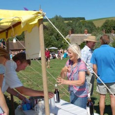 Pimms_stall Crhis Gieves, Caroline Coe, Richard Brown Pimms stall on The Green. Chris Gieves serves, Caroline Coe purchases.