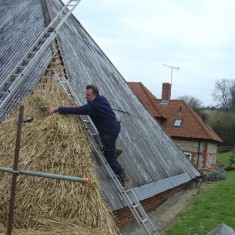Lyle Morgan thatching corner of barn