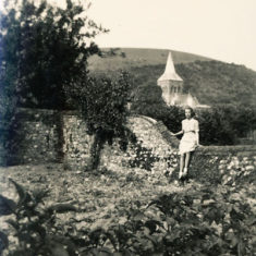 Olivia Woodfield on wall with church behind, WWII