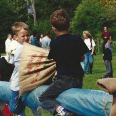 Boys sack-fighting on slippery pole Boys sack-fighting on slippery pole