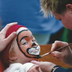 Girl having face painted, pointing Girl having face painted